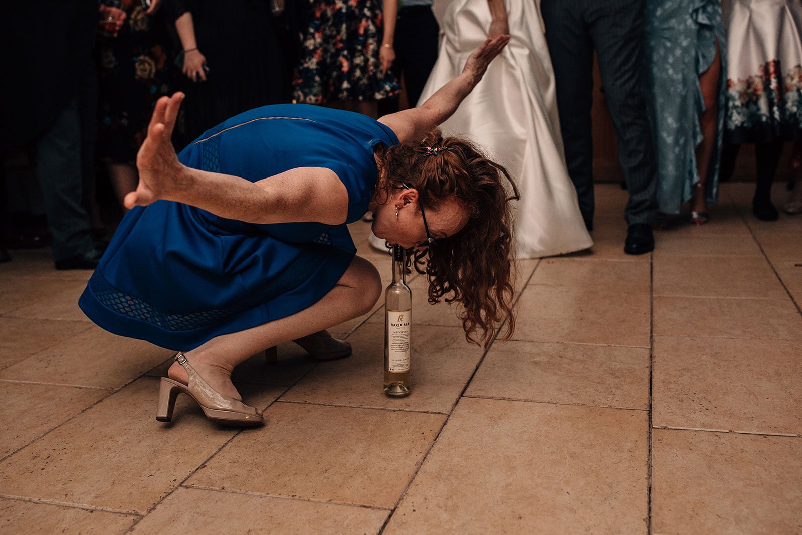 Wild dance-floor photograph of girl drinking out of a bottle with no hands at Delbury Hall photography in Shropshire