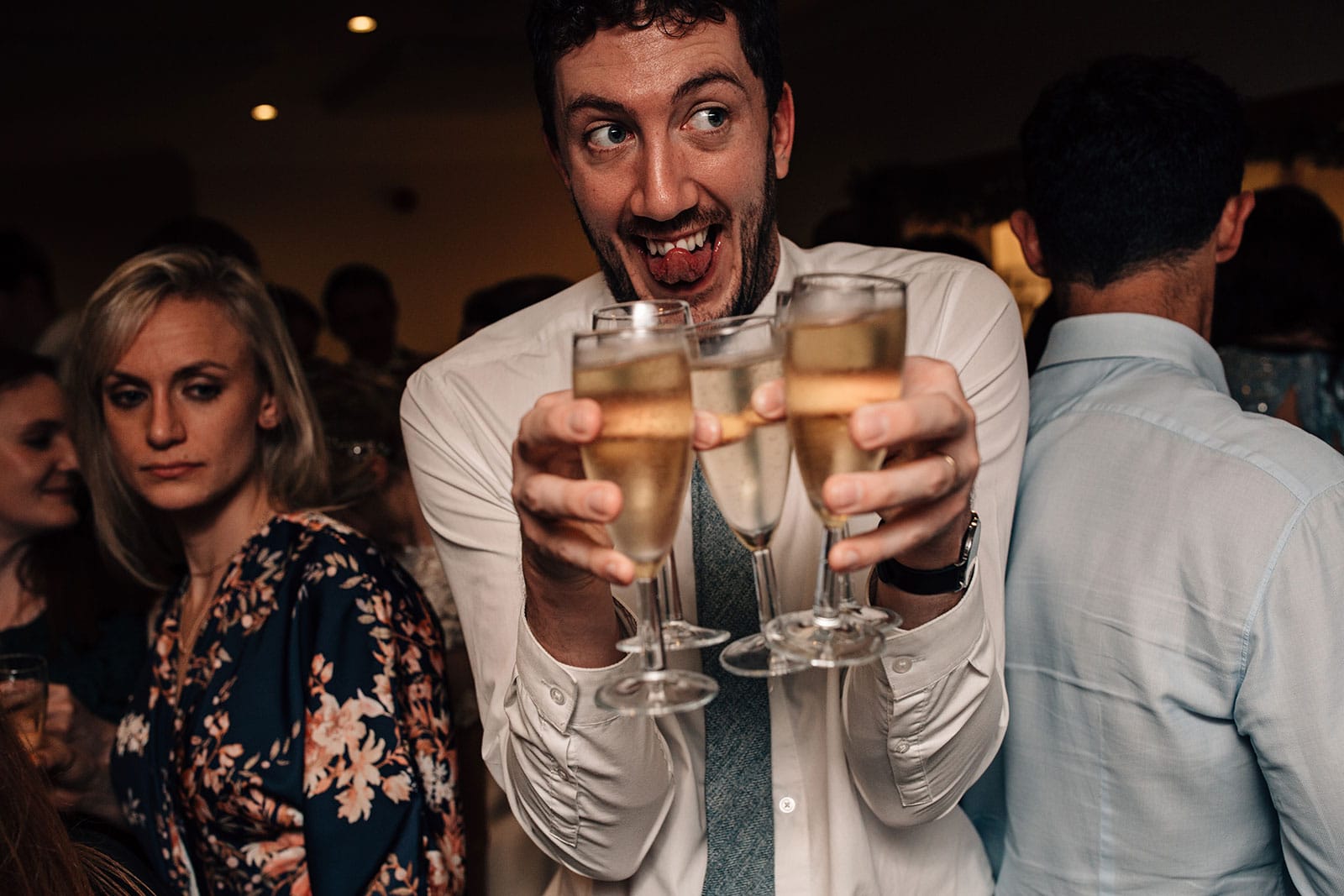 Fun wedding photography of a wedding guest carrying too many drinks