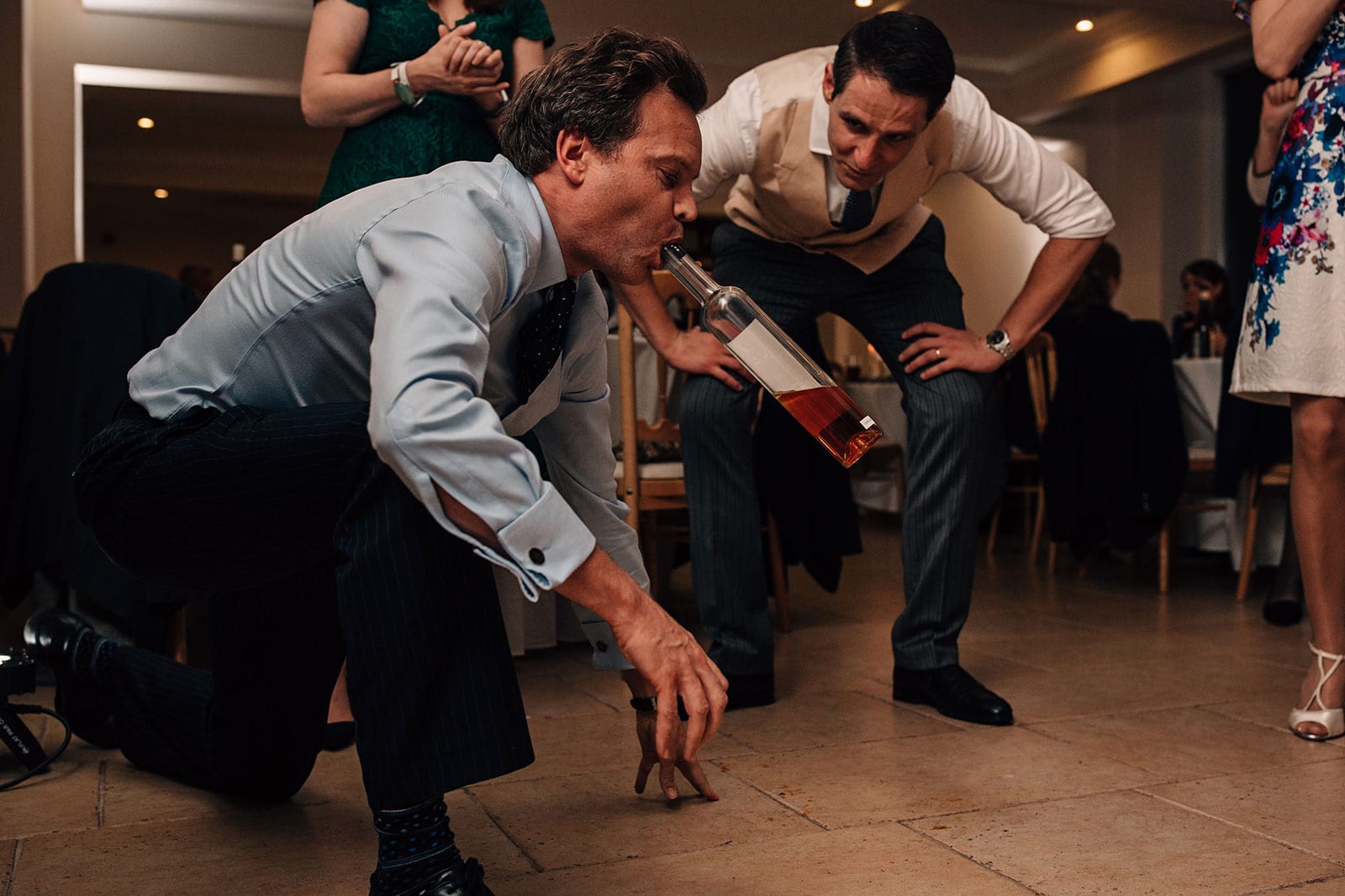 Alternative wedding dance-floor photography capturing the madness after dark with a photograph of a man drinking spirits from the bottle