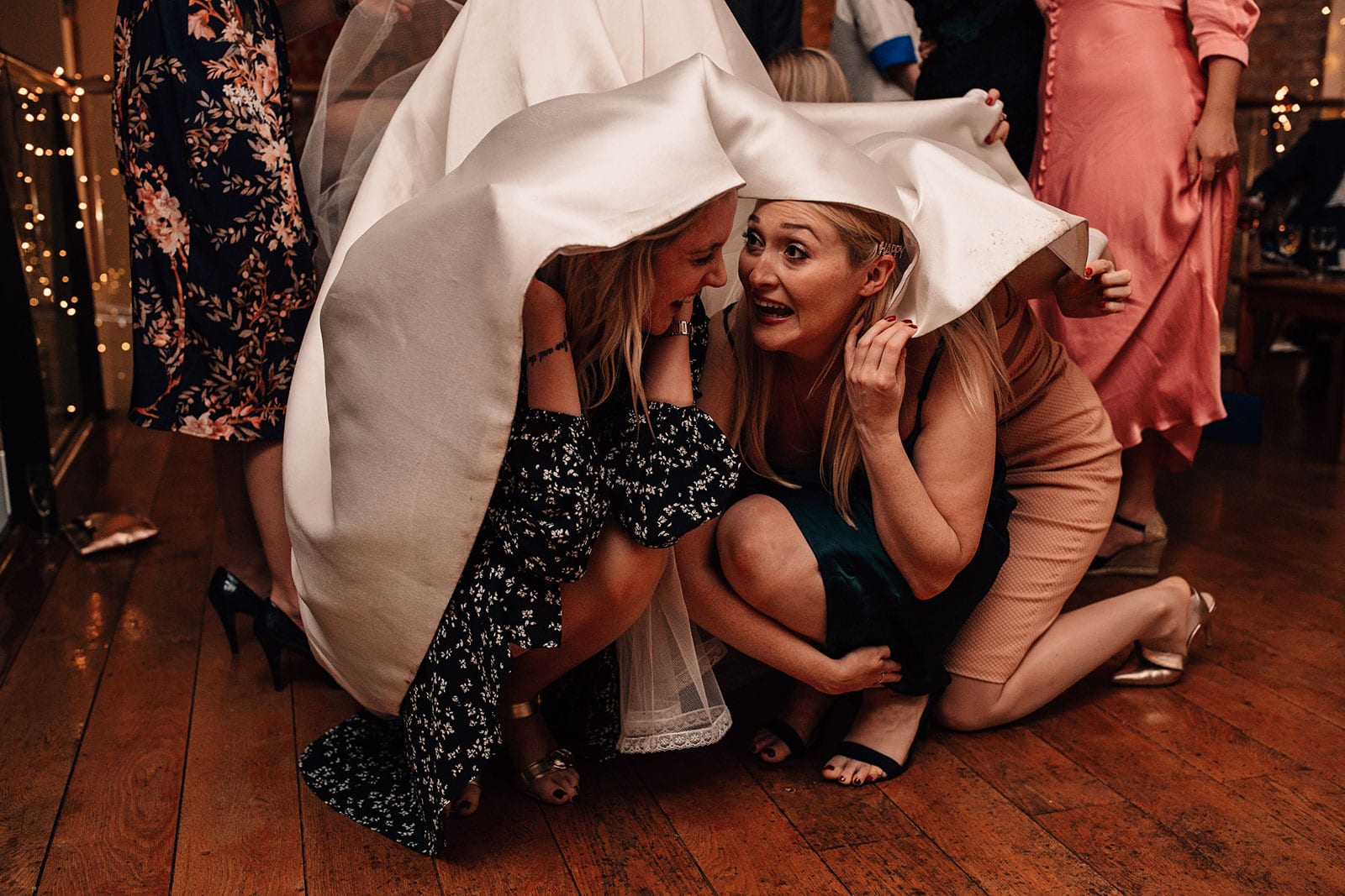 Guests hiding under the brides wedding dress