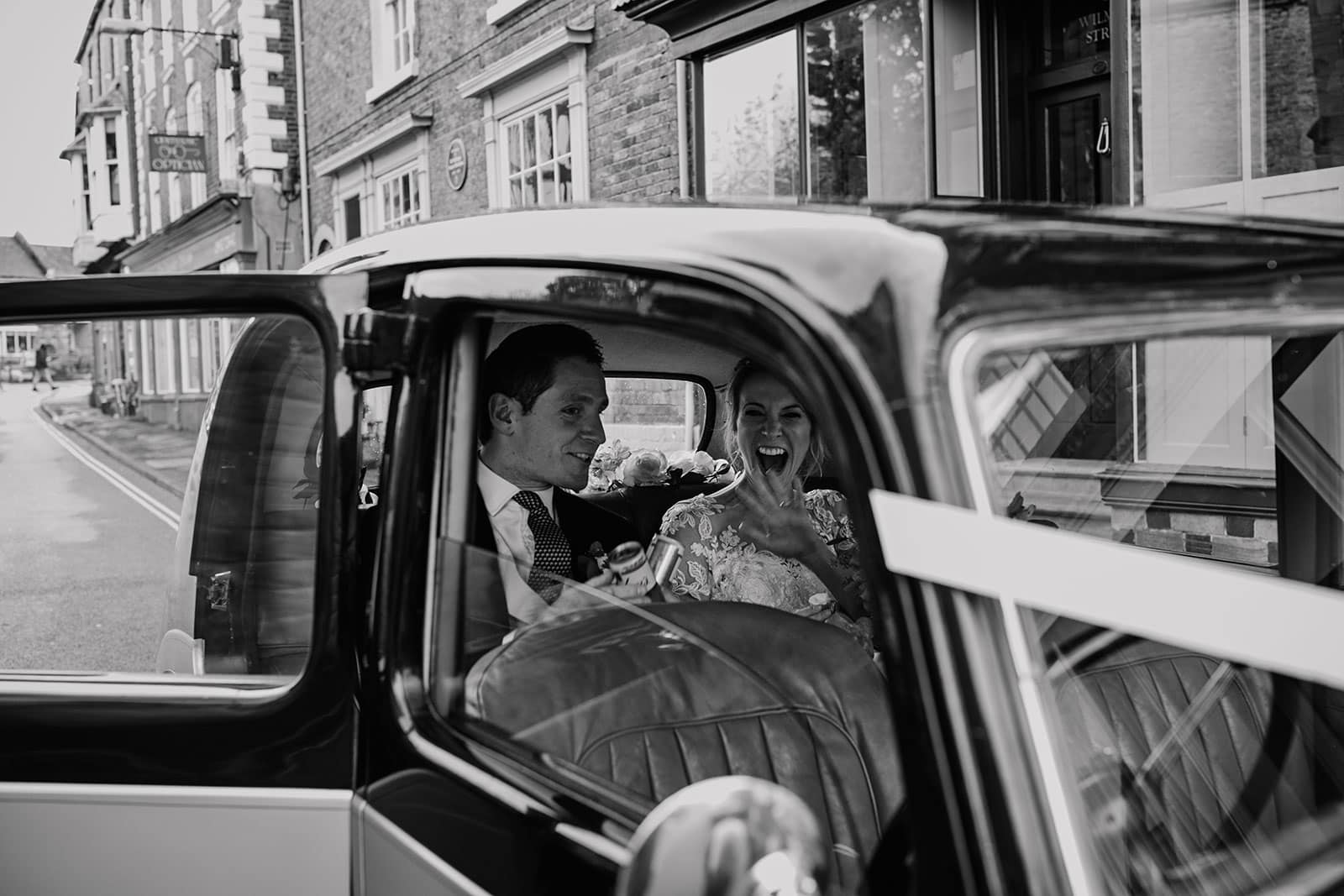 Black and White image of the bride and groom in their vintage wedding car