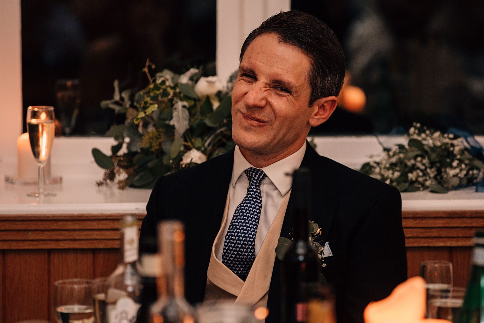 The groom screwing up his face in reaction to the best man's wedding speech
