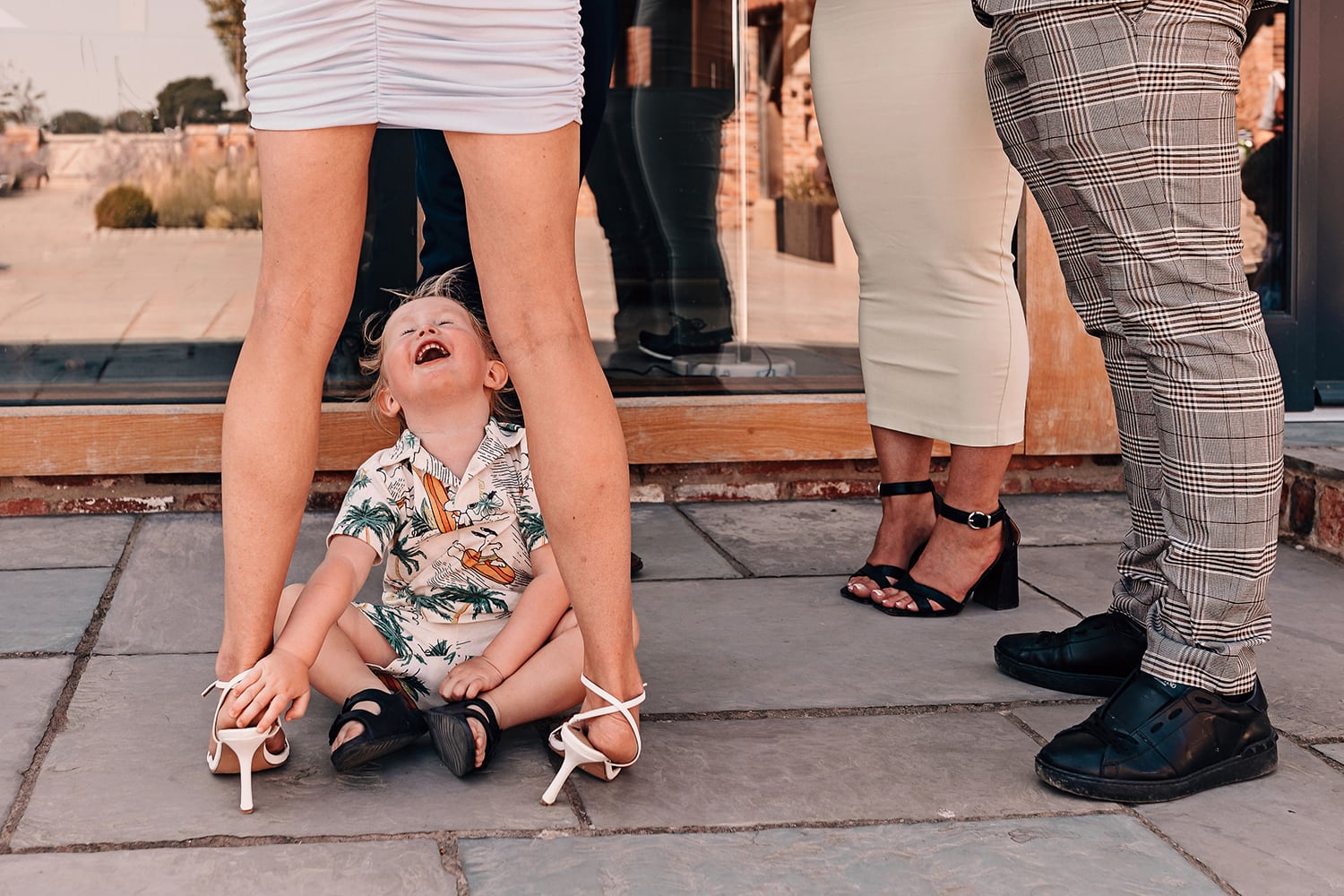 Funny photograph of a small child looking up someones skirt at a wedding