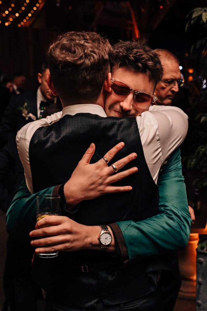 Documentary style close up photograph of a wedding guest hugging the Groom