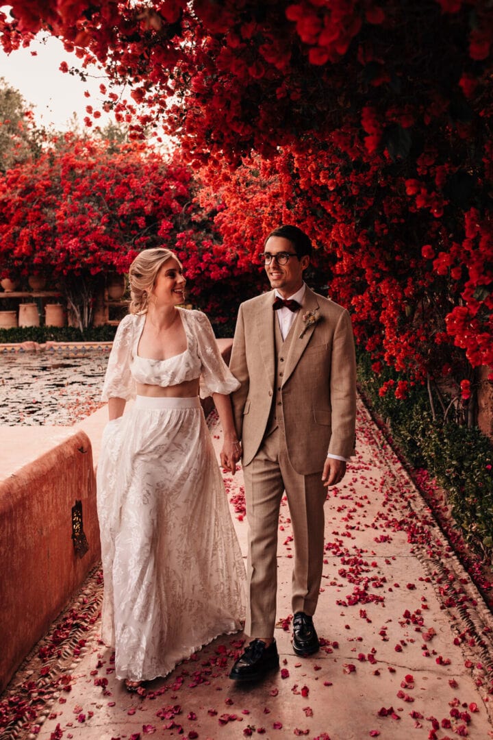 Newlywed couple under red floral trees in Marrakesh