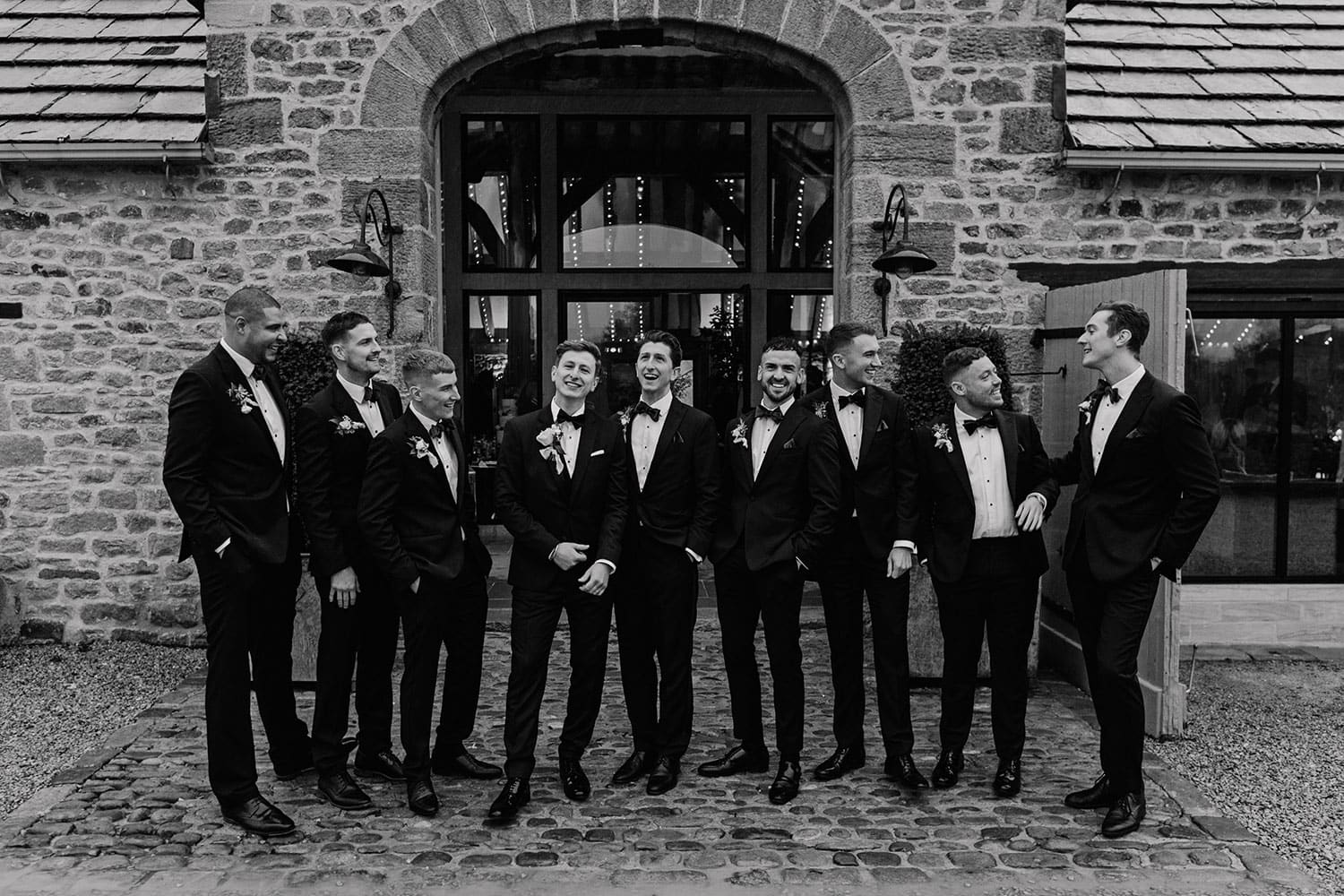 Black and White wedding photograph of Groomsmen infront of The Tithe barn, Bolton Abbey
