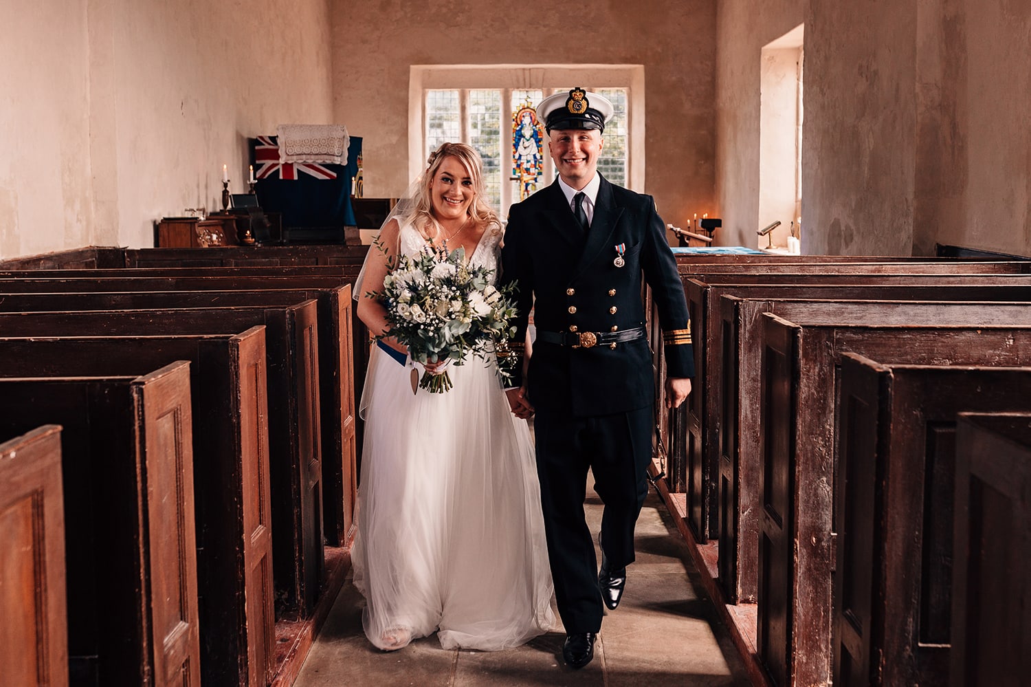 Newlyweds exiting church dressed in wedding gown and Coastguard uniform