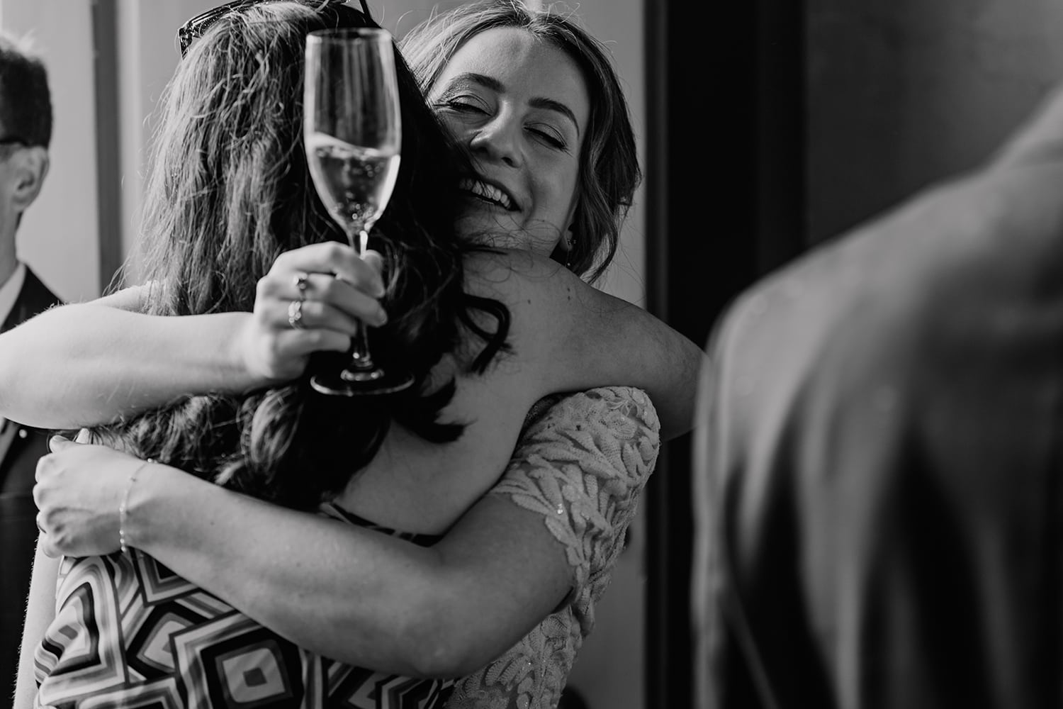 Documentary style Black and white image of a Bride hugging a guest