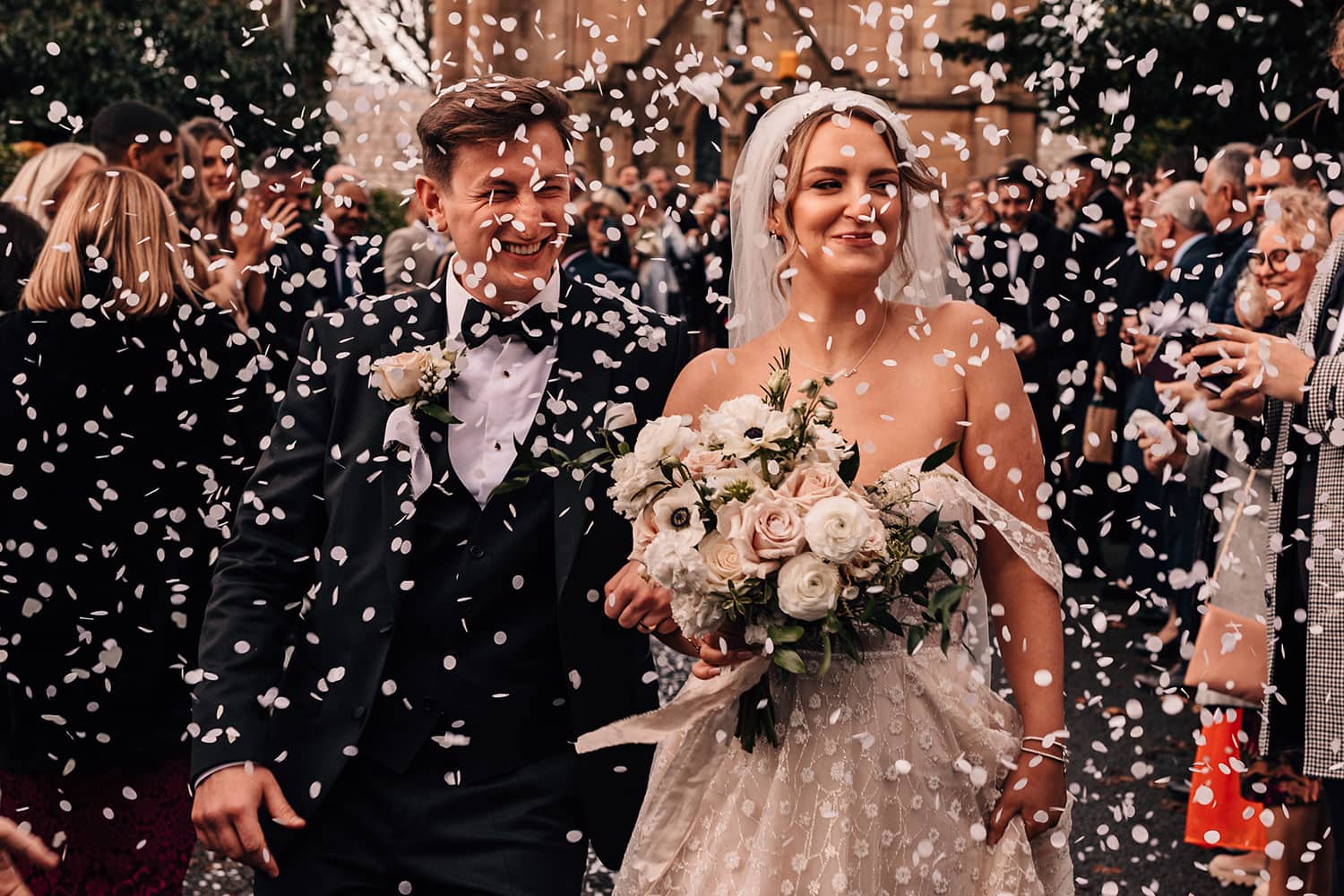 Bride and Groom walking toward the camera in a storm of confetti