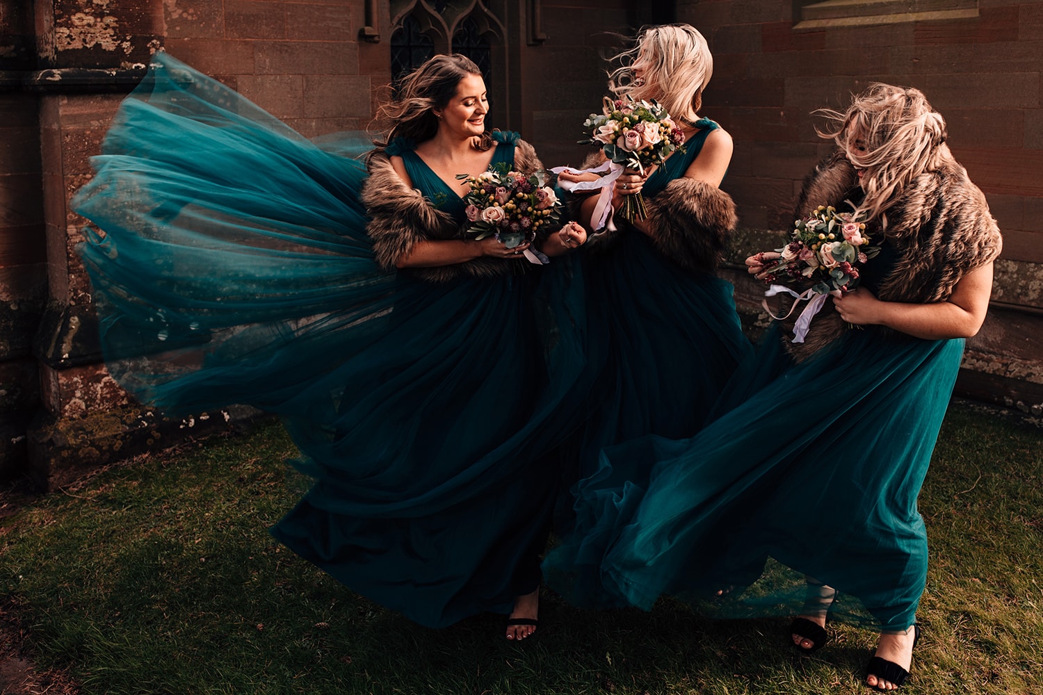 Award winning image of three bridesmaids battling the wind with their emerald dresses