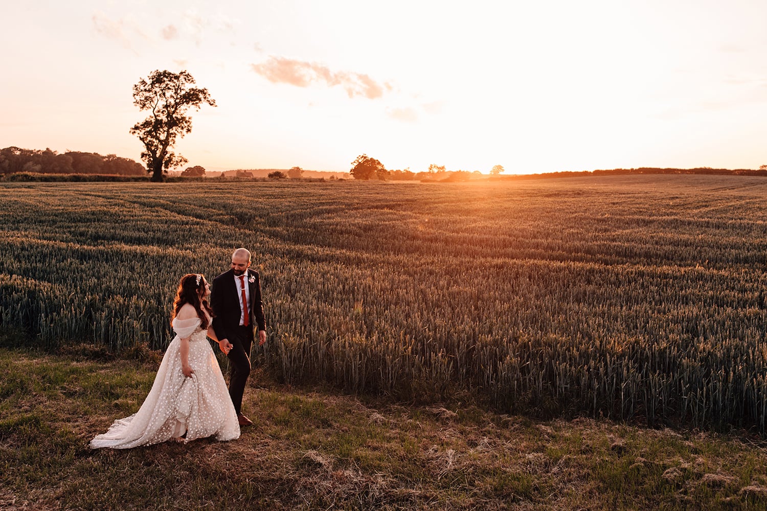 Landscape photograph of the sunset with Bride and Groom walking into the distance