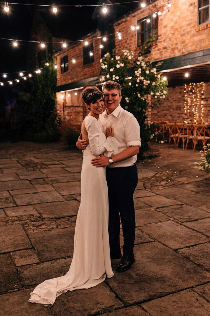 Wedding photograph of Bride and Groom in low light under a sea of festoon lights