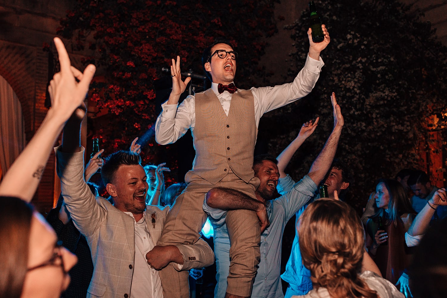 Groom on his guests shoulders on the wedding dance-floor