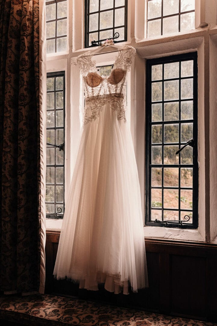 Silhouette of lace wedding dress hanging in the window