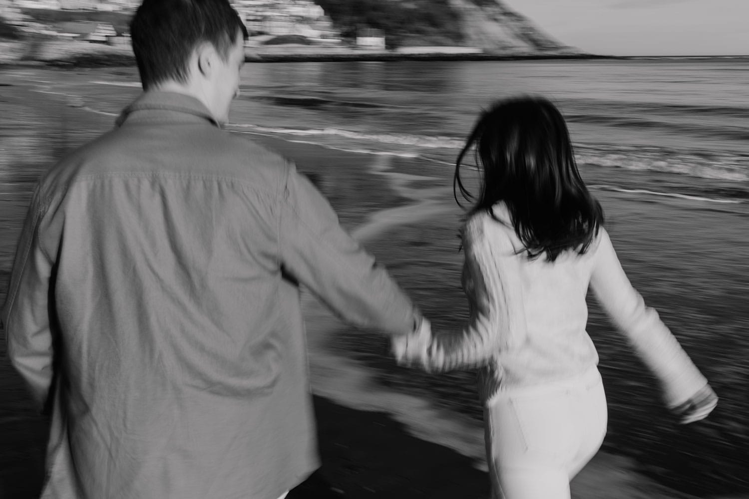 Artistic black and white image of couple running along the beach during the pre-wedding photo-shoot